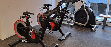 Un gimnasio con bicicletas estáticas y vistas al exterior.