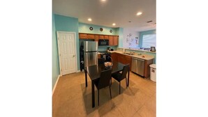 A compact kitchen with a refrigerator, microwave, and wooden cabinets. - DISNEY R US! UNIVERSAL IS TOO!!! (Kissimmee)