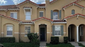 A two-story house with a beige facade, red-tiled roof, and a front entrance. - DISNEY R US! UNIVERSAL IS TOO!!! (Kissimmee)