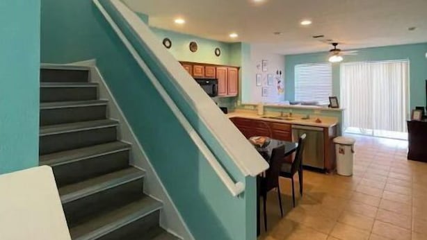 A staircase leading to a kitchen area with a dining table and chairs. - DISNEY R US! UNIVERSAL IS TOO!!! (Kissimmee)