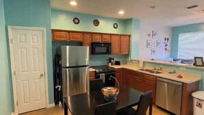 A compact kitchen with a refrigerator, microwave, and wooden cabinets.