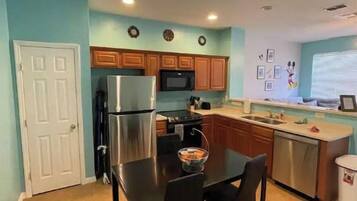 A compact kitchen with a refrigerator, microwave, and wooden cabinets.