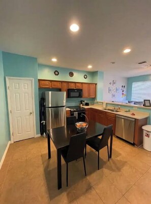 A compact kitchen with a refrigerator, microwave, and wooden cabinets.