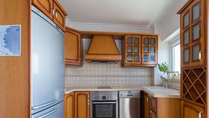 A compact kitchen with wooden cabinets, a built-in oven, a dishwasher, and a refrigerator. - Tufia Marine Life by Canariasgetaway (Telde)