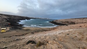 A rocky coastal landscape with a beach and a lighthouse. - Tufia Marine Life by Canariasgetaway (Telde)