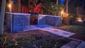 An outdoor patio area with stone walls, a fire pit, and a small seating area. - Poolside Cocoa Oasis with Tiki Bar (Port Saint John)