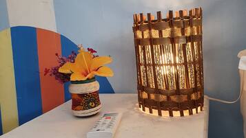 Un tavolo bianco con un telecomando, un vaso decorativo con fiori e un candelabro acceso.
