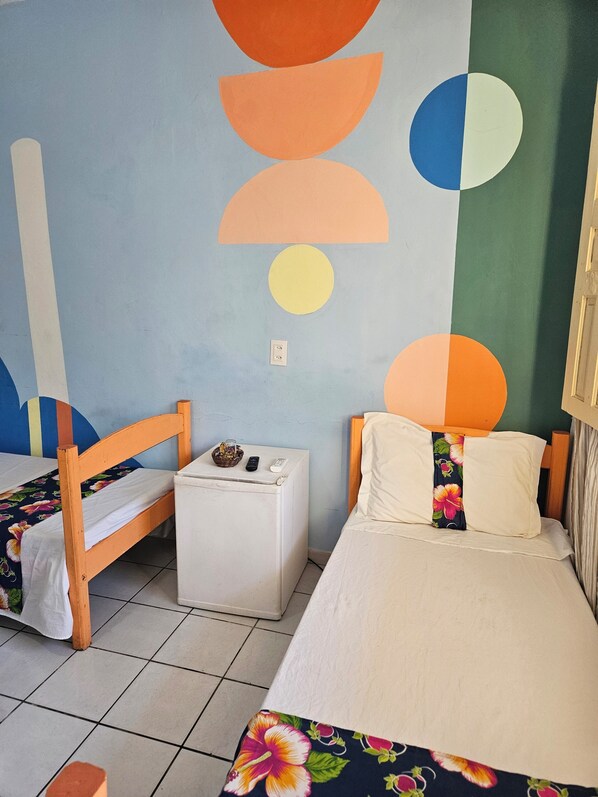 A room with two beds, a small white table, and a wall with geometric patterns.