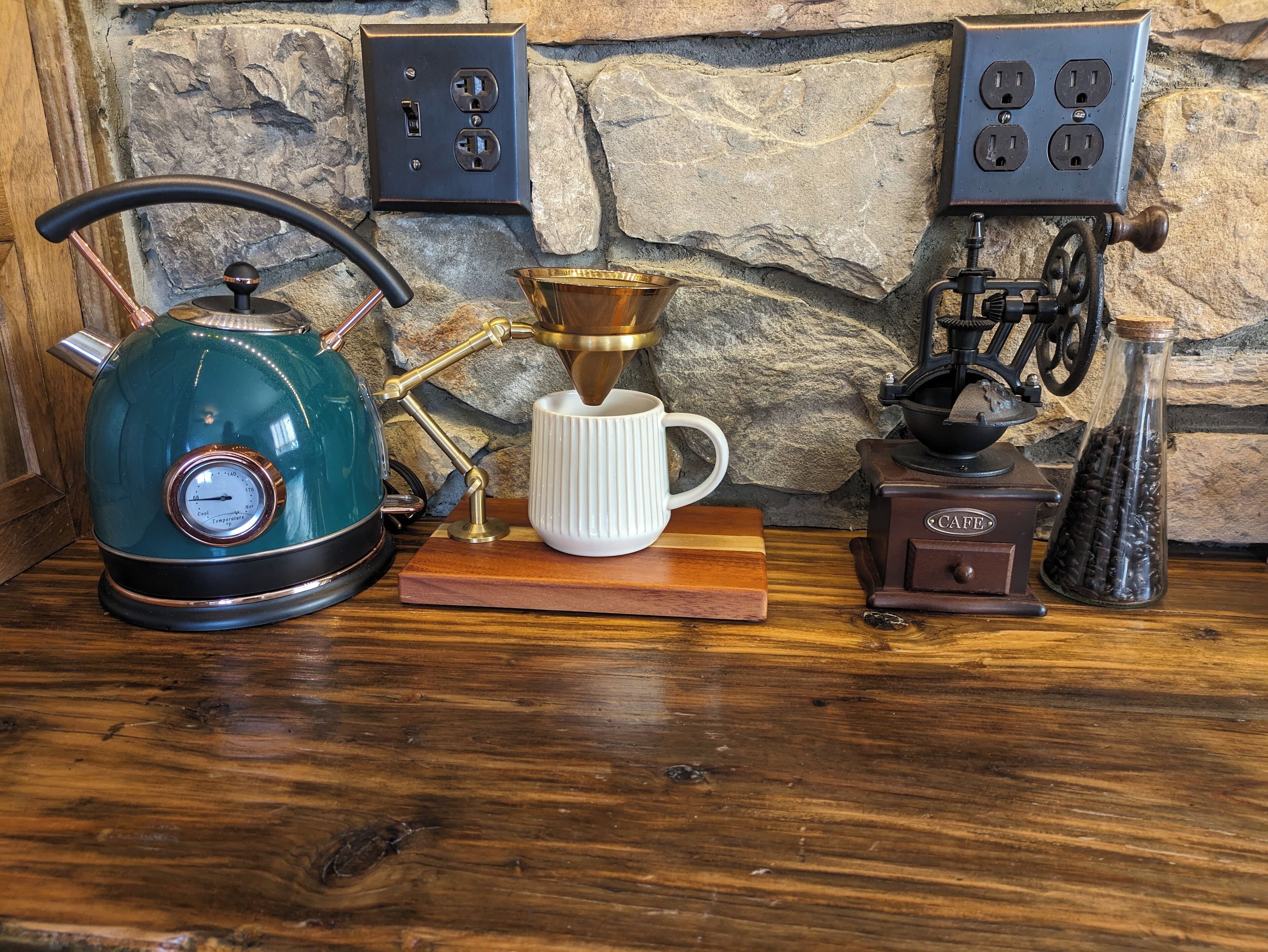 A kitchen counter with a kettle, coffee maker, and grinder.
