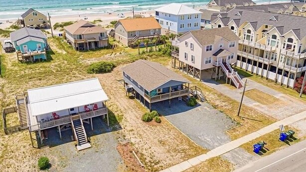 A coastal residential area with houses, some elevated on stilts, and a beach in the background. - Newly Renovated Beach Bungalow - 3 minute walk to the beach! (Surf City)