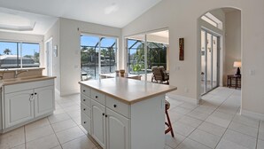 Una cocina amplia con una isla grande, armarios blancos y vistas al exterior.