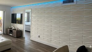 Un salon moderne doté d’un mur à texture originale, d’un téléviseur à écran plat, d’un meuble en bois et d’un canapé.
