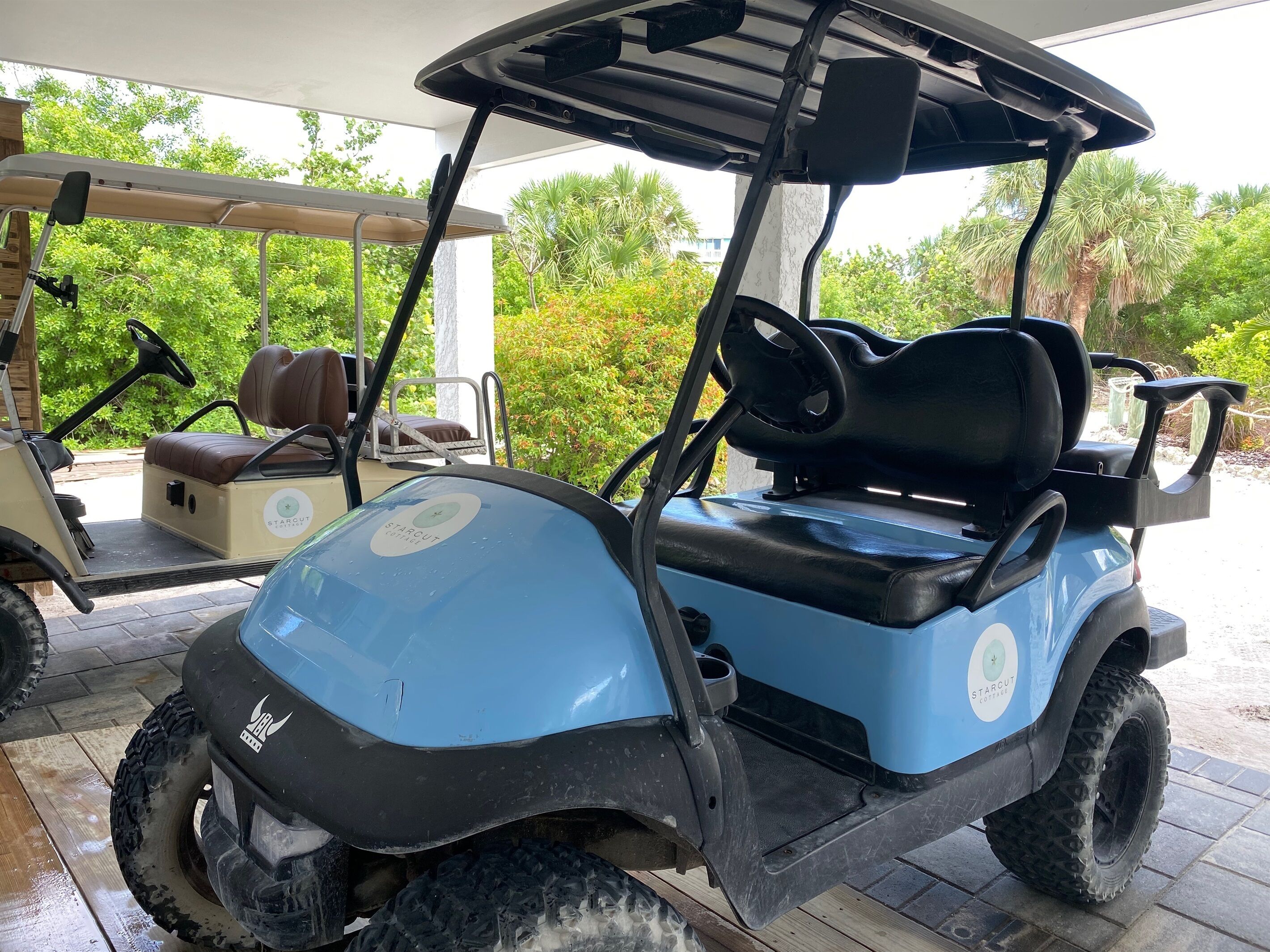 A blue golf cart with a StarCut logo, parked on a wooden deck with a covered area in the background.