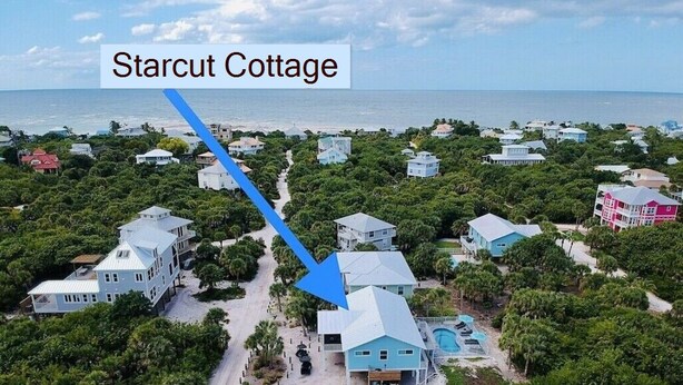 Vue aérienne de Starcut Cottage, une propriété située en bord de mer, comprenant plusieurs maisons, une piscine et offrant une vue dégagée sur l’océan.