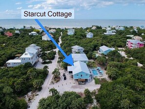 Vista aérea de Starcut Cottage, una propiedad frente al mar con varias casas, una piscina y una vista despejada del océano.