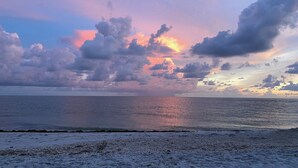 Une plage avec une mer calme et un ciel au coucher du soleil.