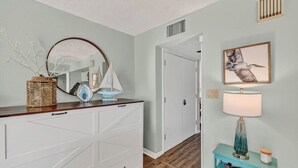 A hallway with a white dresser, a mirror, a framed picture, and a blue console table with a lamp.