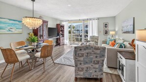 A spacious living room with a dining area, a sofa set, and a kitchen area.