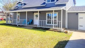 A two-story house with a covered porch, a small attached garage, and a well-maintained lawn.