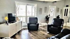 A living room with a sofa, two armchairs, a TV, and a small table.