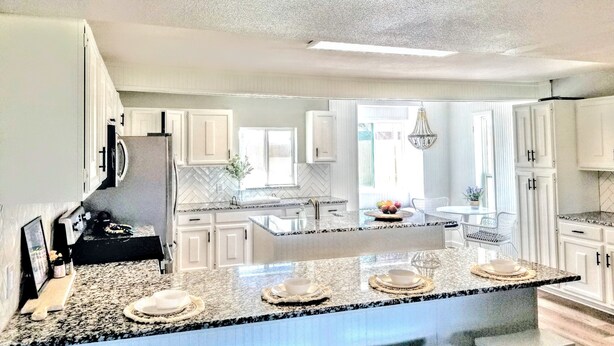 A modern kitchen with white cabinetry, granite countertops, and a central island with seating.