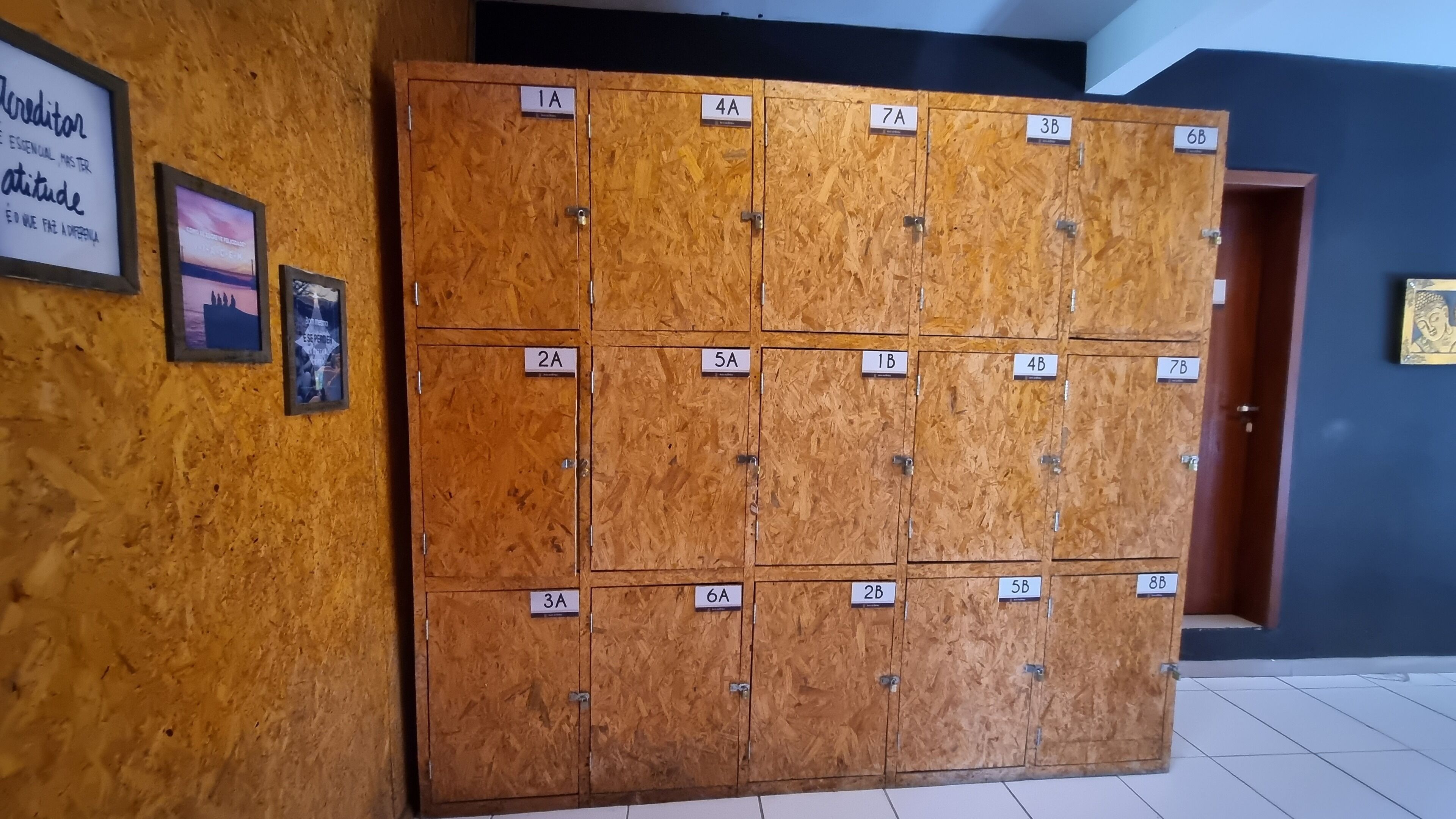 A row of wooden lockers with numbered labels, a Buddha statue, and motivational posters on the wall.