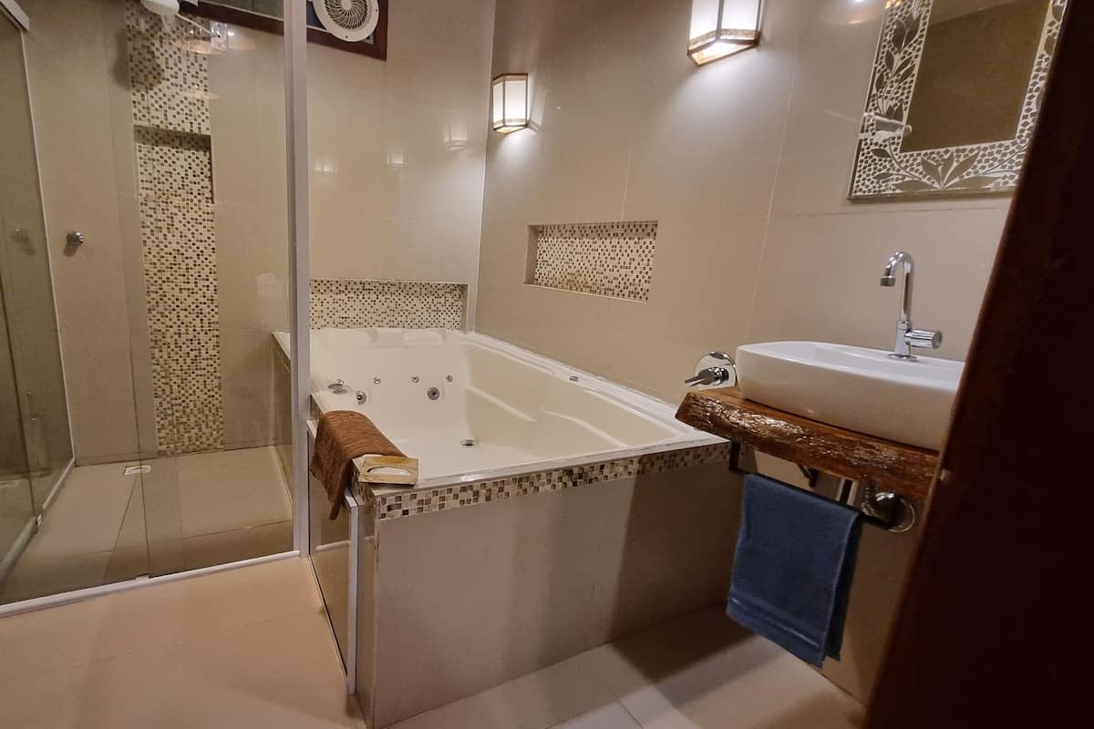 Une salle de bain moderne dotée d’une douche à parois de verre, d’une baignoire sur pieds et d’un lavabo avec un plan de travail en bois.