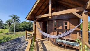 A wooden cabin with a hammock on the porch, a wooden deck, and a view of the surrounding greenery. - Arte da Tribo Hsotel & Camping - Hostel (Imbituba)