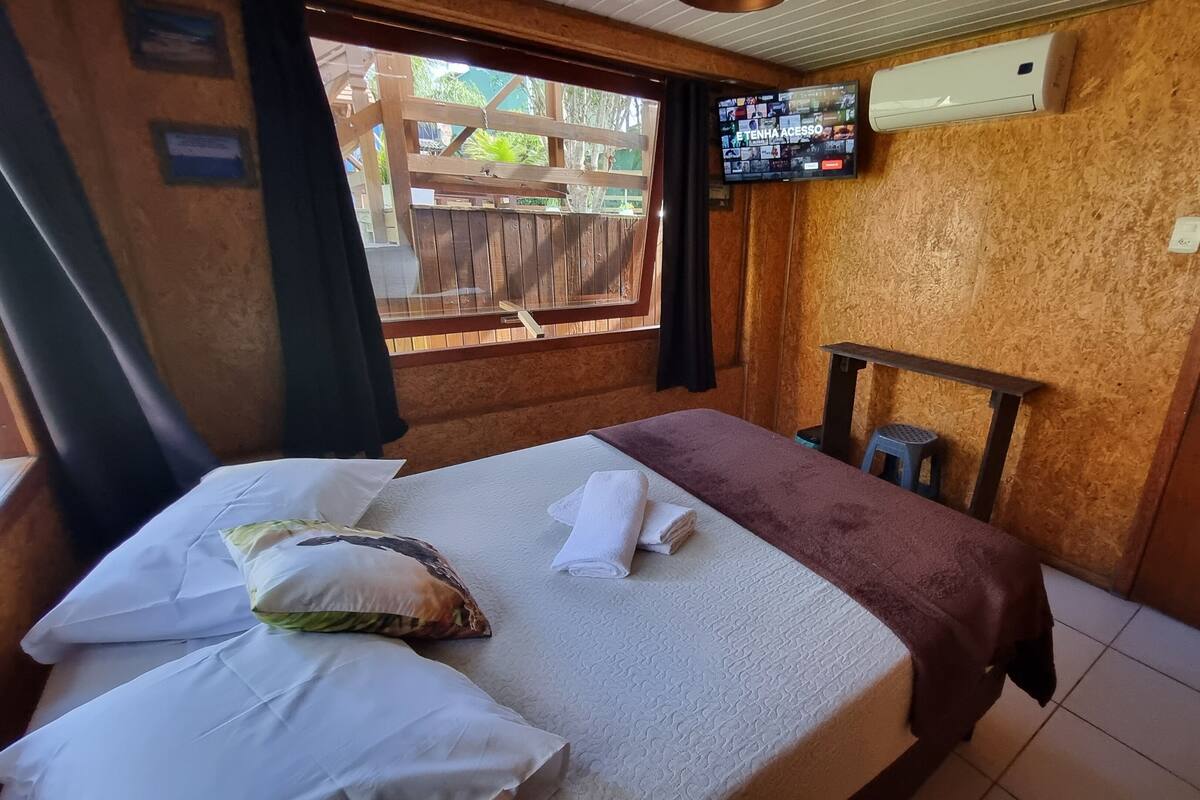 Une chambre avec un lit, un téléviseur fixé au mur et une porte en bois.
