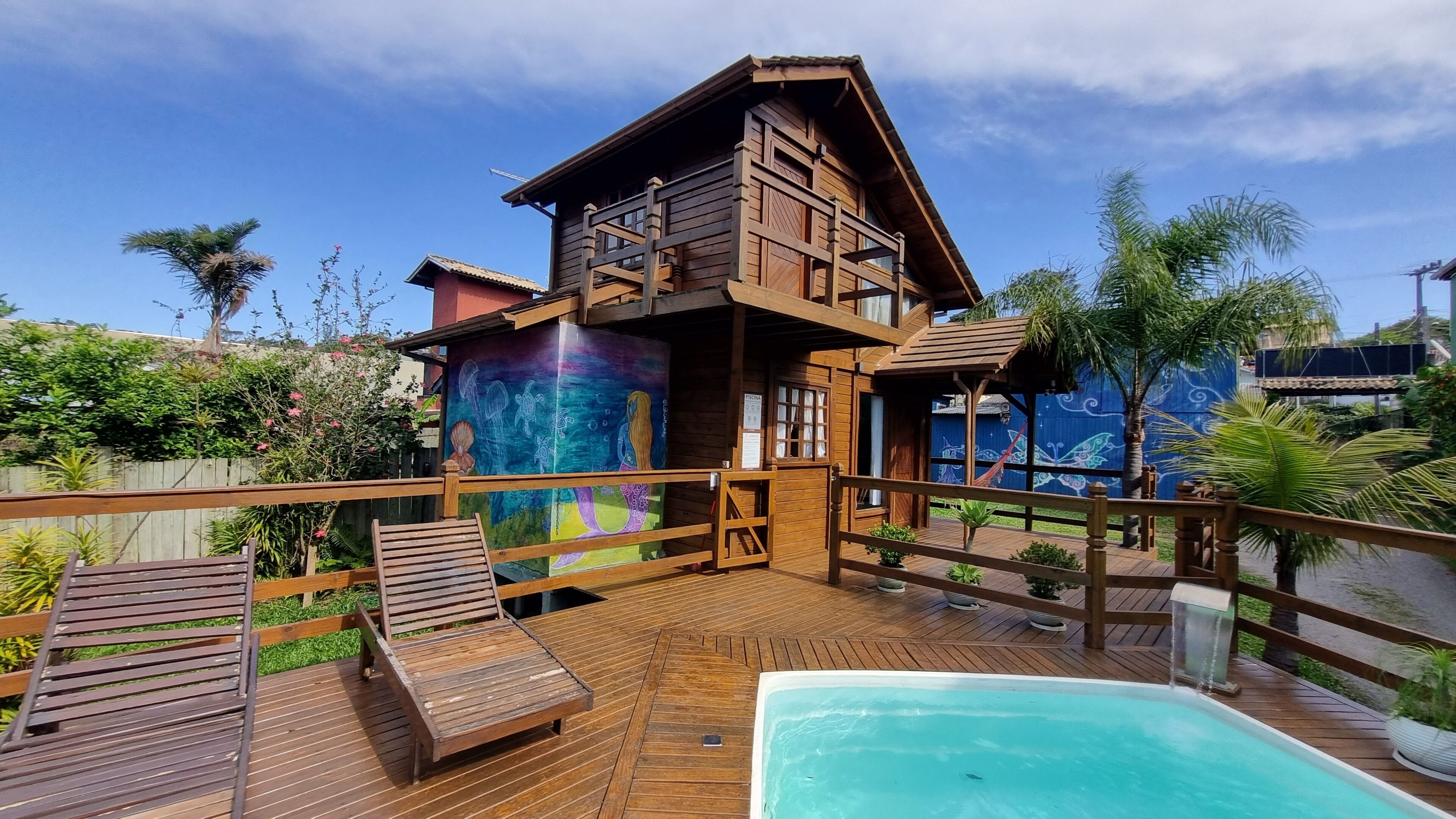 A wooden villa with a pool, deck, and a mural on the side.