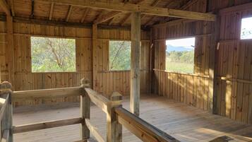 A wooden cabin with a wooden deck, large windows, and a view of the outdoors.