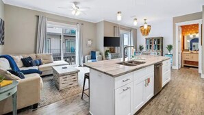 A modern kitchen with a central island, white cabinetry, and a dining area with a sofa and coffee table.