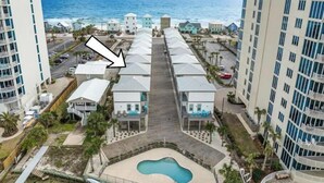 A hotel with a pool, beachfront view, and a parking area.