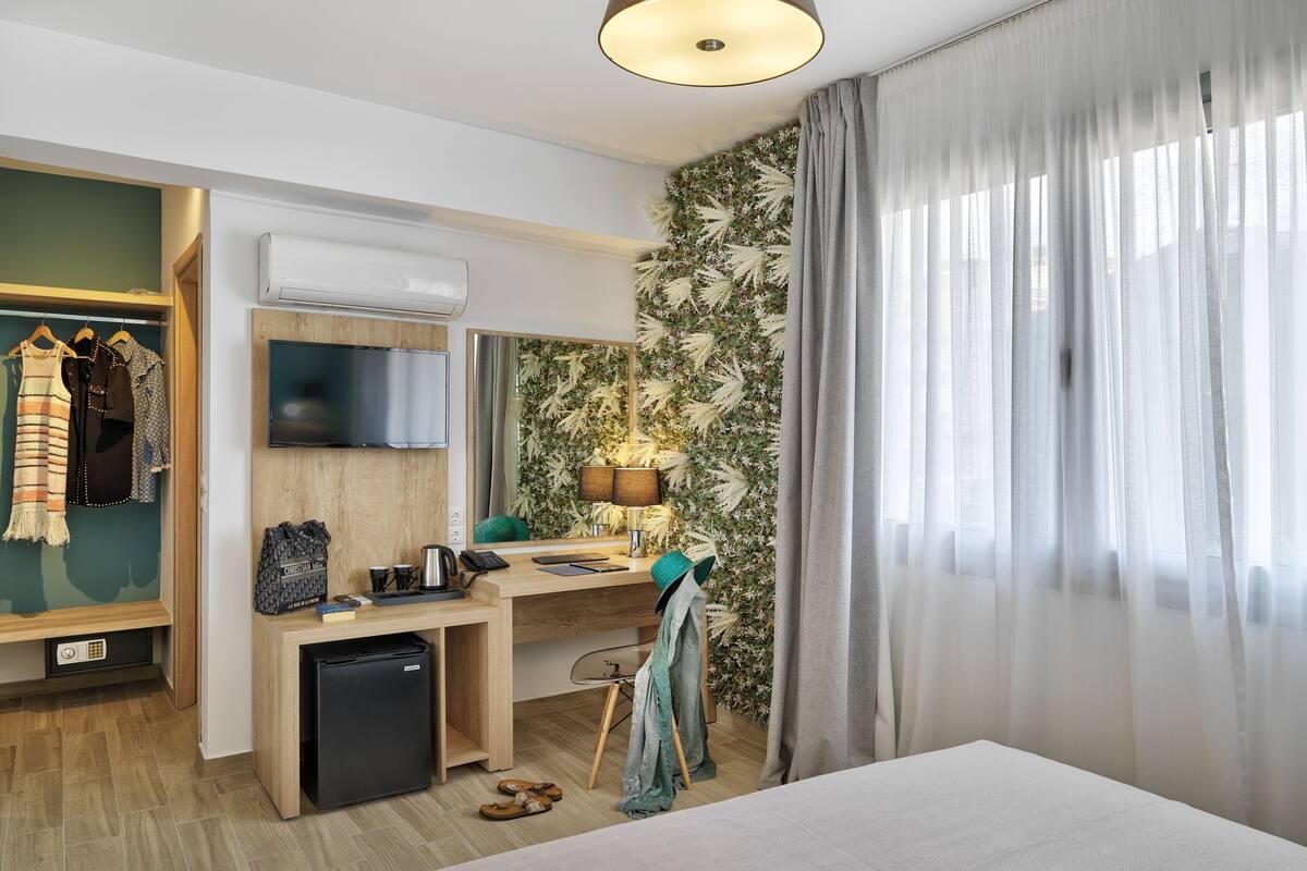 A hotel room with a bed, a desk with a computer, a TV, and a wardrobe.