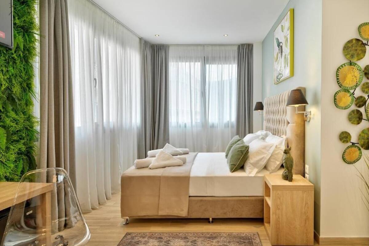 A modern bedroom with a bed, bedside table, and a large window with curtains.