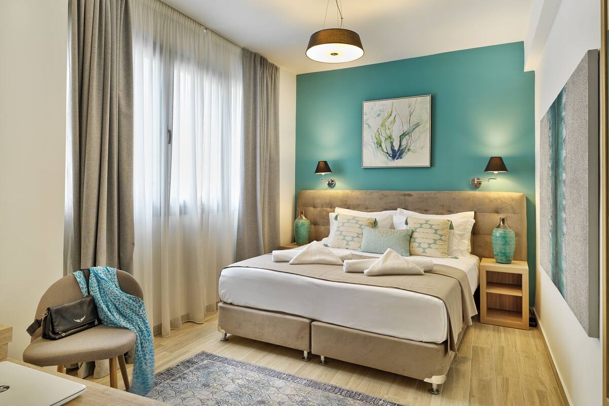 A modern bedroom with a bed, bedside tables, a chair, and a desk.