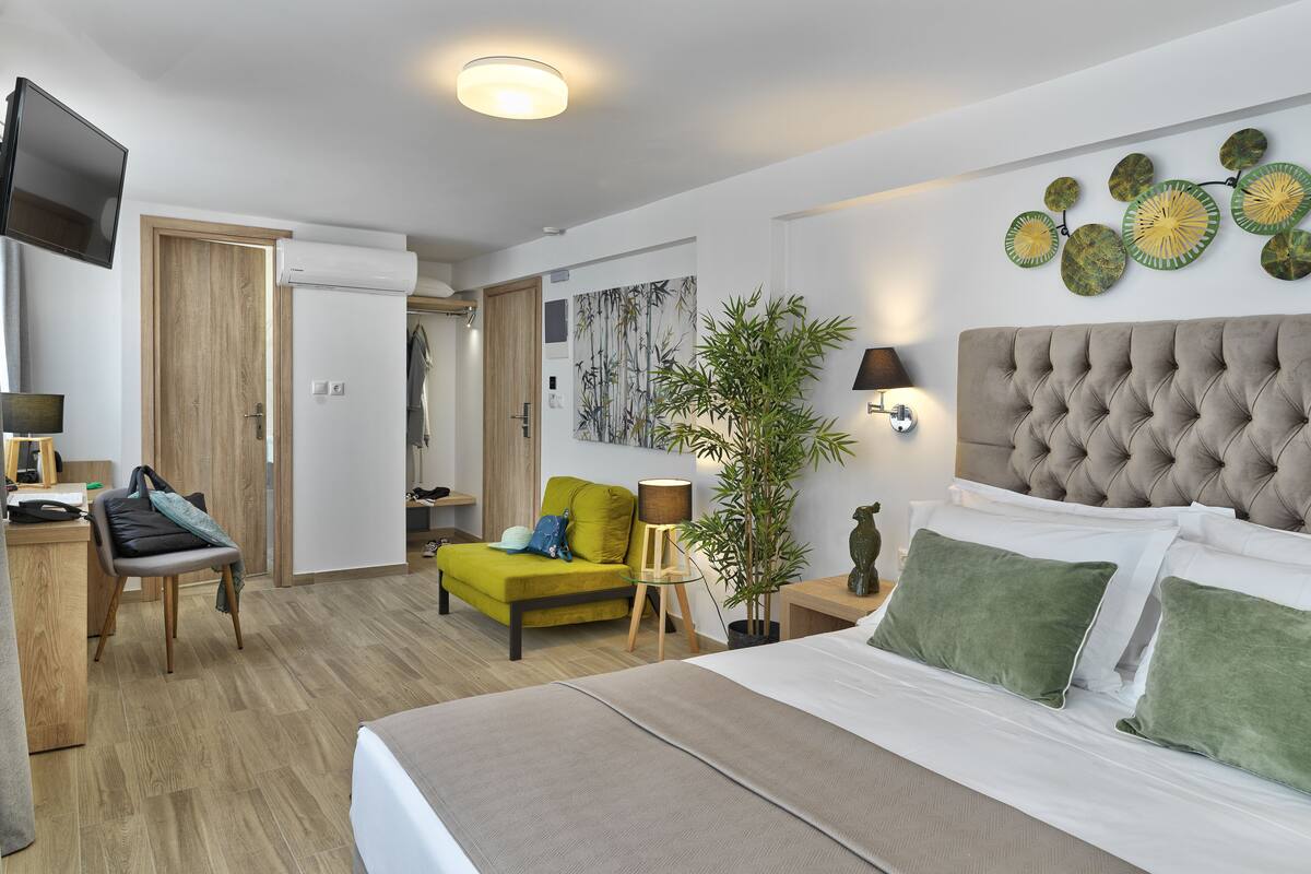A modern hotel room with a bed, a desk, a chair, a television, and a bathroom.