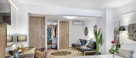 A modern hotel room with a bed, a sofa, a dining area, and a walk-in closet.