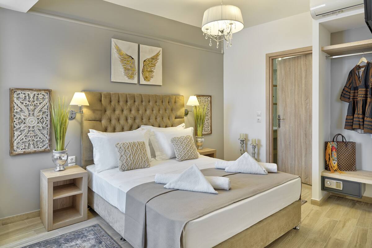 A neatly arranged bedroom with a large bed, bedside lamps, decorative wall art, and a wardrobe.