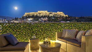A rooftop terrace with a sofa, a round coffee table, and a decorative vase. - ACROPOLIS CITY LIFE BH (Athens)