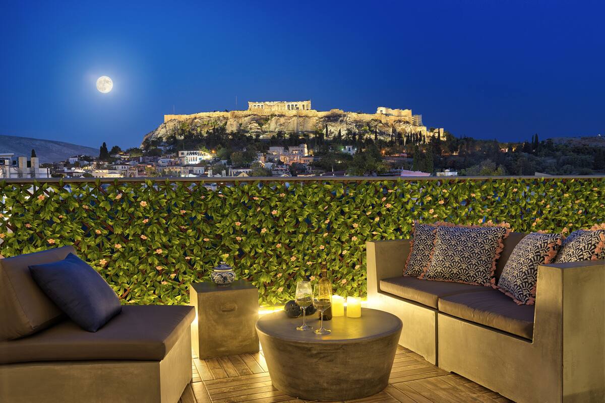 A rooftop terrace with a sofa, a round coffee table, and a decorative vase.