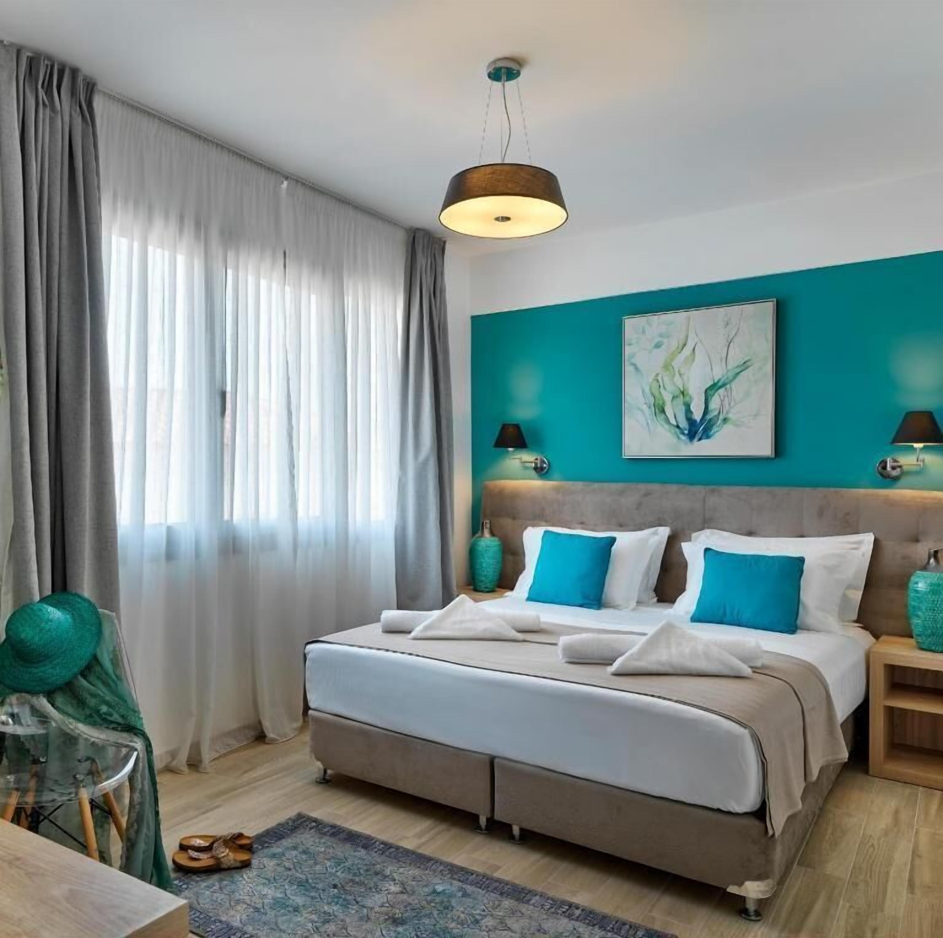 Une chambre moderne avec un grand lit, un mur d’accent de couleur turquoise et un luminaire au plafond.
