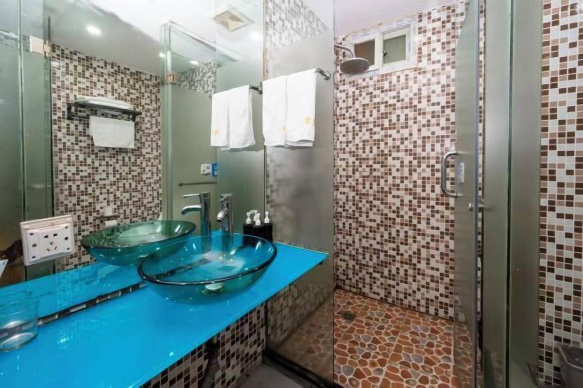 A bathroom with a glass bowl sink, a shower with mosaic tiles, and a mirror.