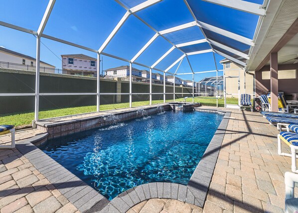 Une piscine couverte avec un bassin aux eaux d’un bleu limpide, entourée de chaises longues et d’une terrasse en briques.
