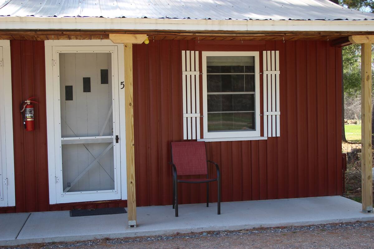 A small building with a red exterior, a white door, and a window with shutters.