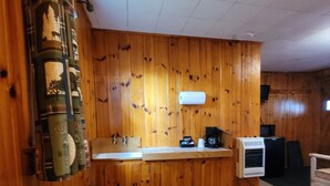 Une pièce aux murs lambrissés, comprenant un coin cuisine avec un évier, un plan de travail et un petit radiateur.