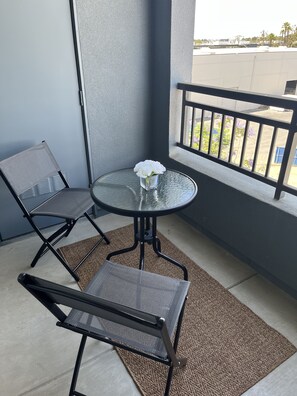 Enjoy a peaceful retreat on this balcony with a glass table and two chairs, perfect for taking in the views.