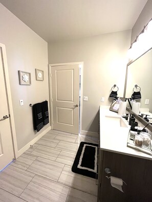 Modern bathroom with a large mirror, white countertop, and black towel rack.