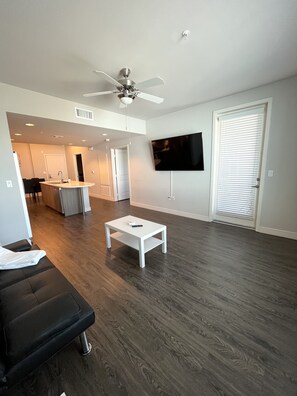 Relax in this stylish living room with a comfortable sofa, flat-screen TV, and ceiling fan.