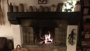 A fireplace with a fire, surrounded by shelves with jars and a Christmas tree decoration. - Charming country house with large barbecue (Gouvy)